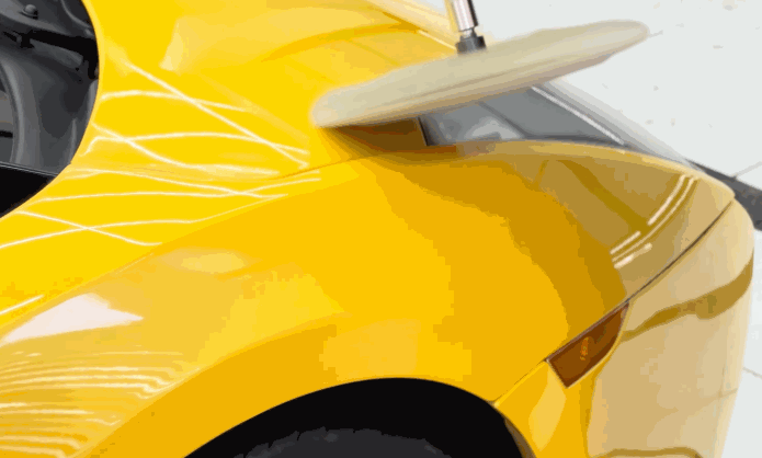 High-speed buffer machine polishing a yellow sports car to refine and cure the ceramic coating, enhancing gloss and durability.