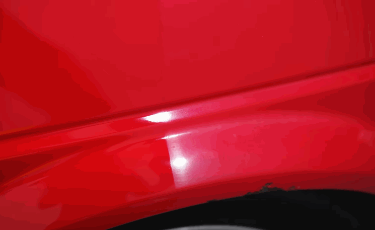 Close-up of a red car panel showing swirl marks and paint defects that must be corrected before ceramic coating is applied.
