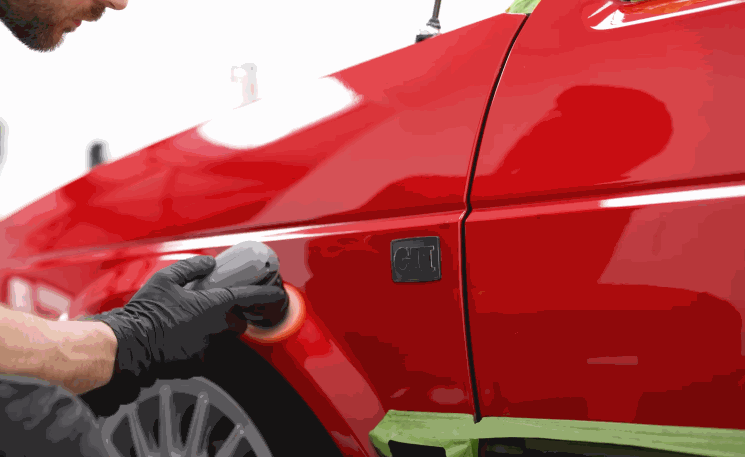 A gloved detailer performs final polishing on a red car fender, ensuring the surface is perfectly prepped for ceramic coating.
